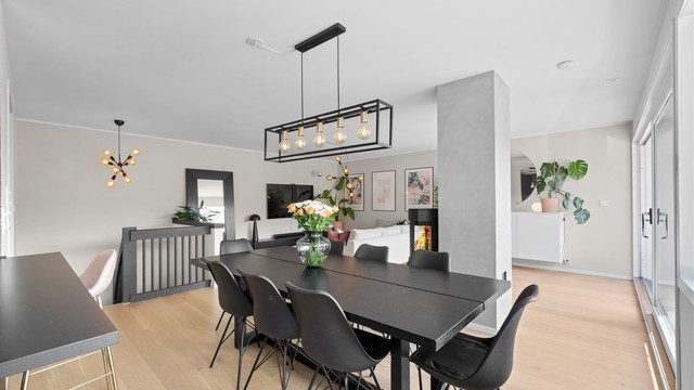 Stue/spisestue sett fra kjøkken. Gjennomgående luftig følelse med peisen som rommets midtpunkt