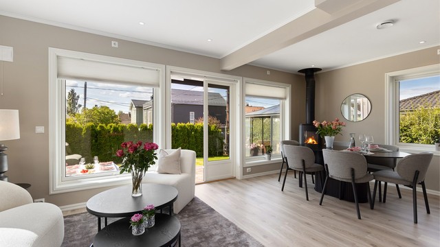 Stuen har en naturlig plassering mot hage og terrasse, og rommer både sofagruppe og spisebord. De store glassflatene mot uteområdet gir en luftig romfølelse og god oversikt når barna leker i hagen