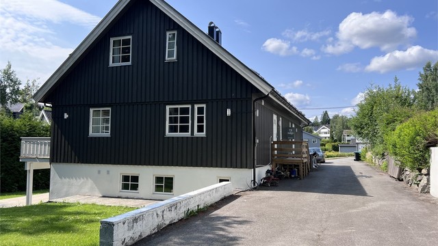 Asfaltert adkomst og gårdsplass med mye biloppstillingsplasser.