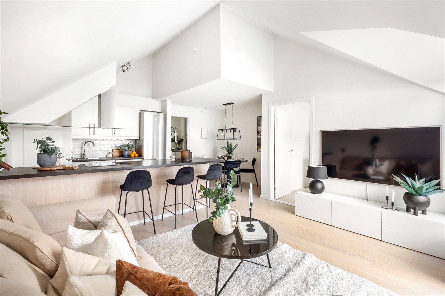 Lys og moderne leilighet med åpen stue- og kjøkkenløsning, stilrene detaljer og store vindusflater som gir en luftig atmosfære.