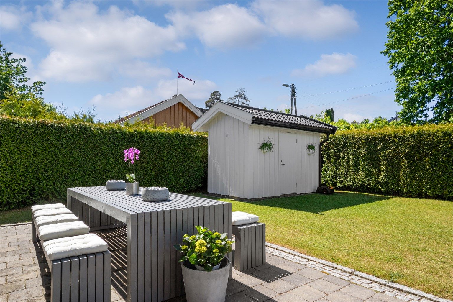 Hagen fremstår nærmest strøken med flere velplasserte prydbusker og levegger med plantekasser på siden mot nordvest. 