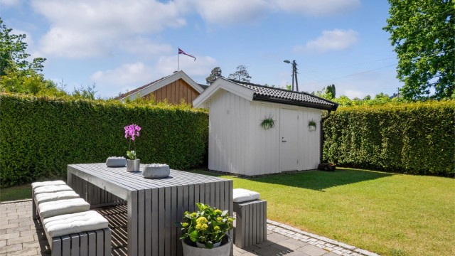 Hagen fremstår nærmest strøken med flere velplasserte prydbusker og levegger med plantekasser på siden mot nordvest.