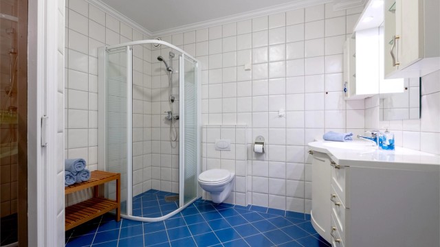 Bad i underetasjen med flislagt gulv med gulvvarme, dusjhjørne og vegghengt toalett.