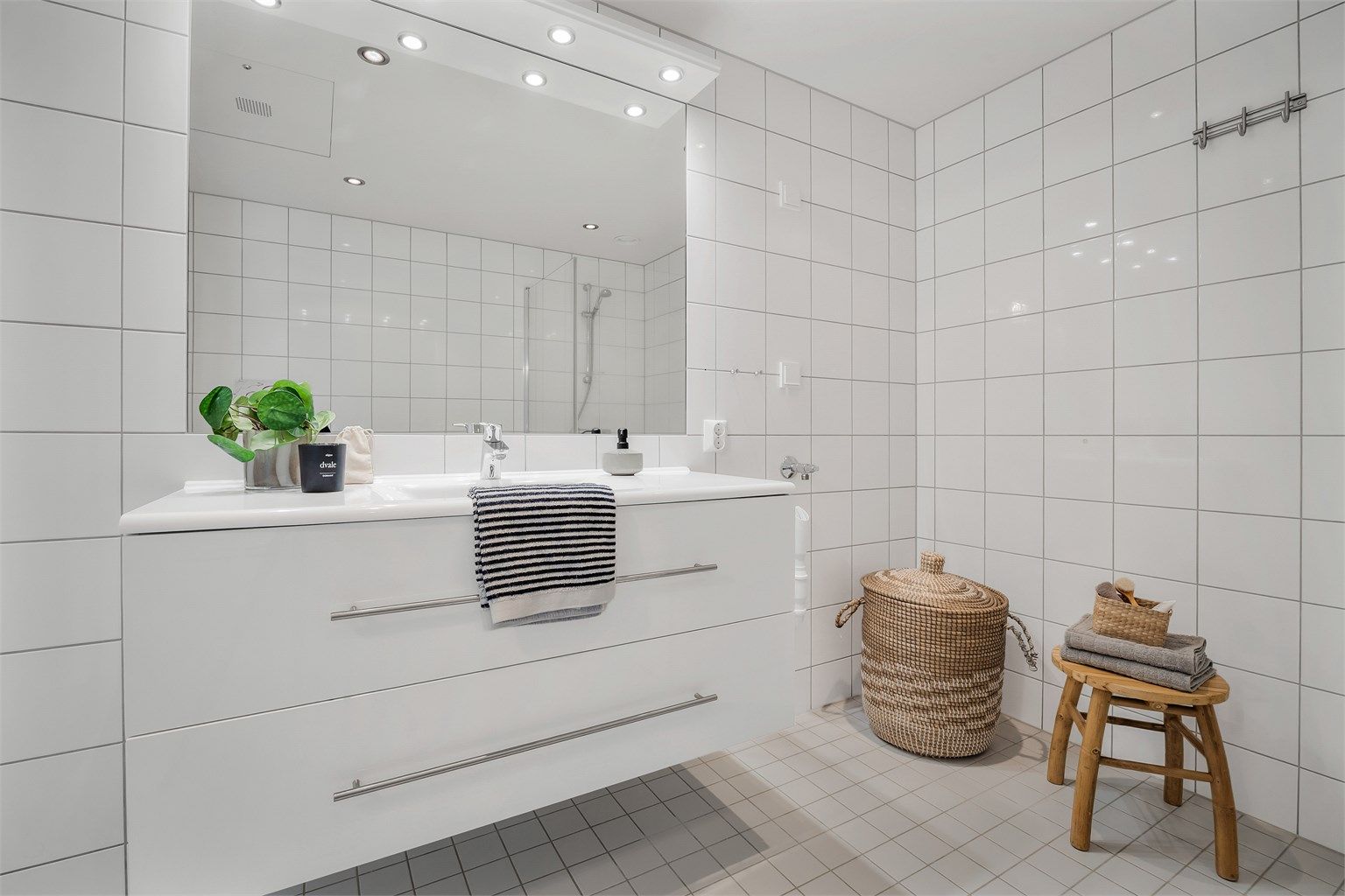 Badet har dusjhjørne med foldedører av glass og opplegg for vaskemaskin.