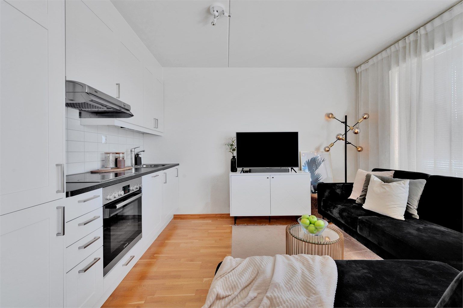 Moderne kjøkken i åpen løsning mot stuen, med hvite skapfronter og benkeplater i laminat.