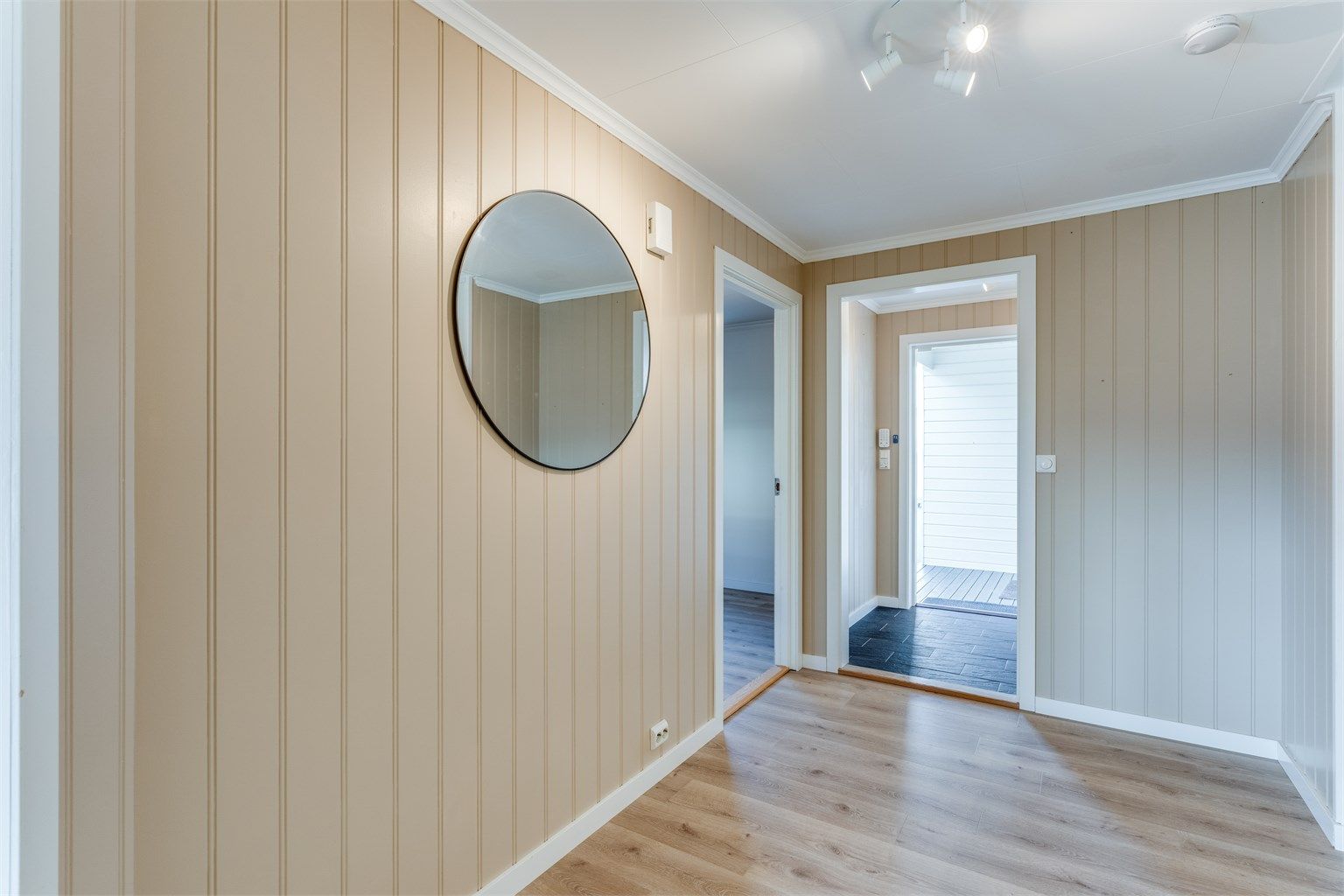 Gang med nyere laminat på gulv, malte veggplater og malte takplater i tak