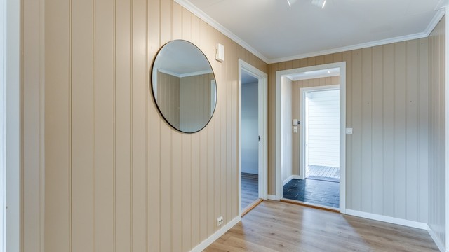 Gang med nyere laminat på gulv, malte veggplater og malte takplater i tak