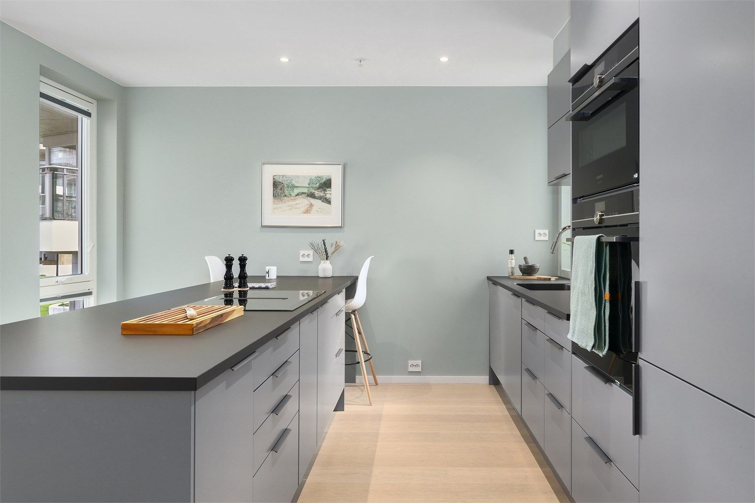 Kjøkkenøyen har oppbevaring på begge sider og er tillaget med barløsning inn mot veggen. Legg merke til at det er vindusåpning på begge sider av kjøkkenet! Foto: Diakrit (Krisztian Sere)