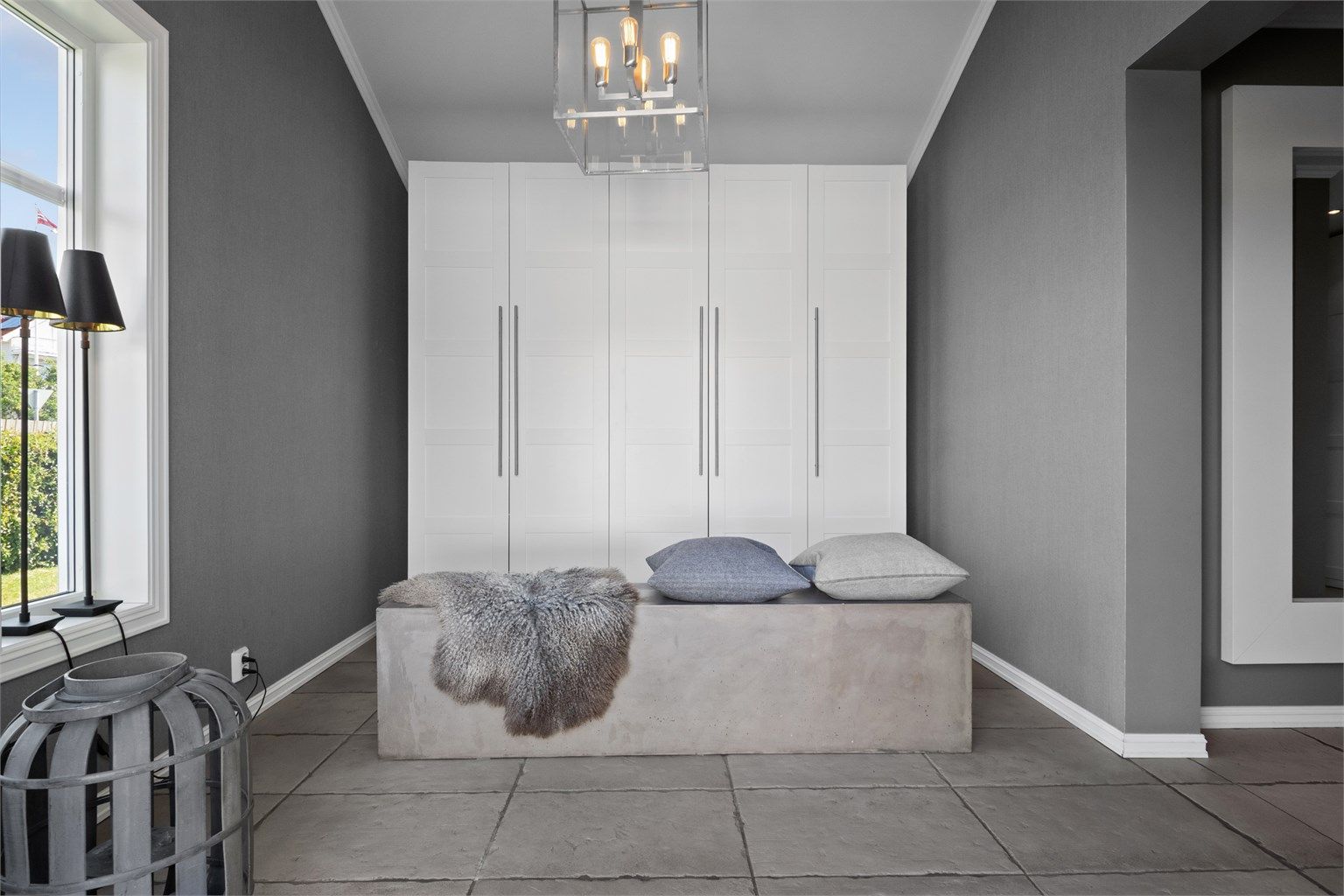 Yttertøyet ryddes enkelt bort i et stort garderobeskap med hvite fronter i profilert utførelse.