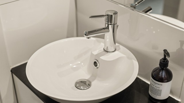 Stilren servantinnredning med speil og overlys gir badet et rent og tidløst uttrykk.