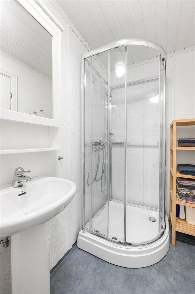 Badet er utstyrt med dusjkabinett, servant og toalett.