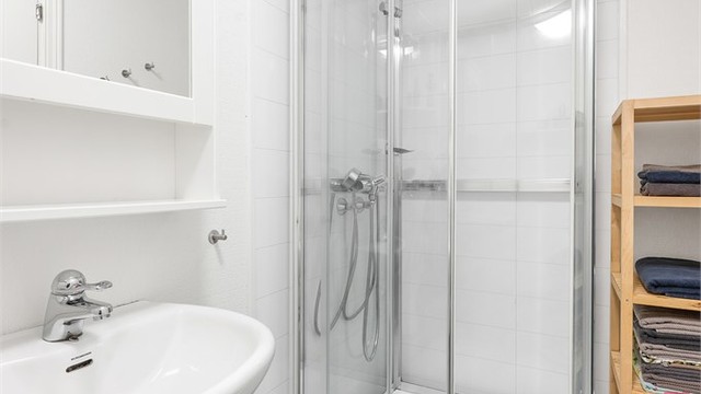 Badet er utstyrt med dusjkabinett, servant og toalett.