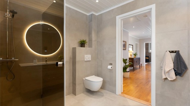 Badet har vegghengt toalett og flislagte overflater med behagelig gulvvarme.