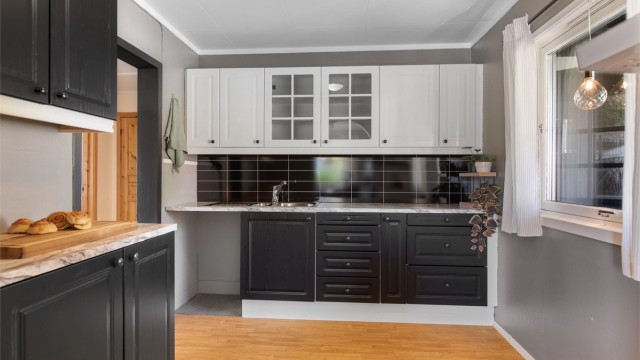 Kjøkkeninnredningen har profilerte fronter, benkeplate med laminert overflate og nedfelt kjøkkenvask med armatur.