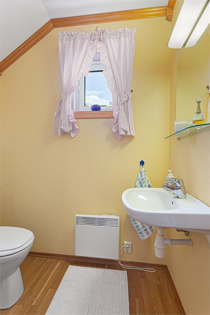 Praktisk toalettrom med vegghengt servant og gulvstående toalett.