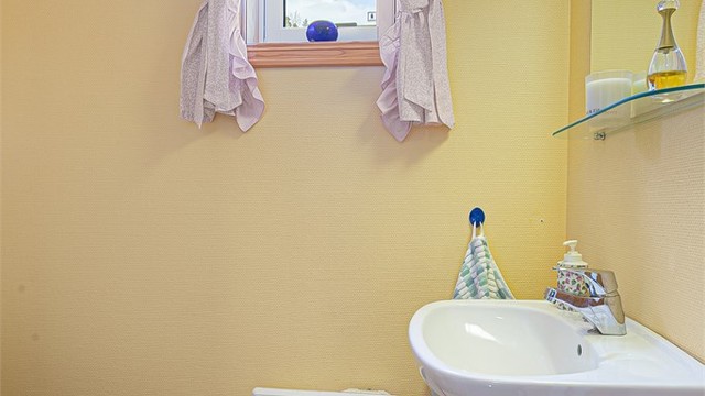 Praktisk toalettrom med vegghengt servant og gulvstående toalett.