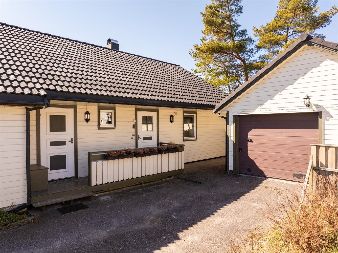 På inngangssiden er det sommerstid sol tidlig på dagen. Entrédøren til høyre, vaskerommets ytterdør til venstre.