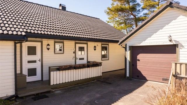 På inngangssiden er det sommerstid sol tidlig på dagen. Entrédøren til høyre, vaskerommets ytterdør til venstre.