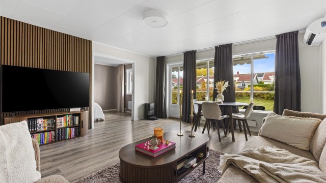 Lys og romslig stue med store vindusflater om slipper inn rikelig med naturlig lys. Fra stuen er det direkte utgang til en rolig og skjermet hage. Foto: A7 media