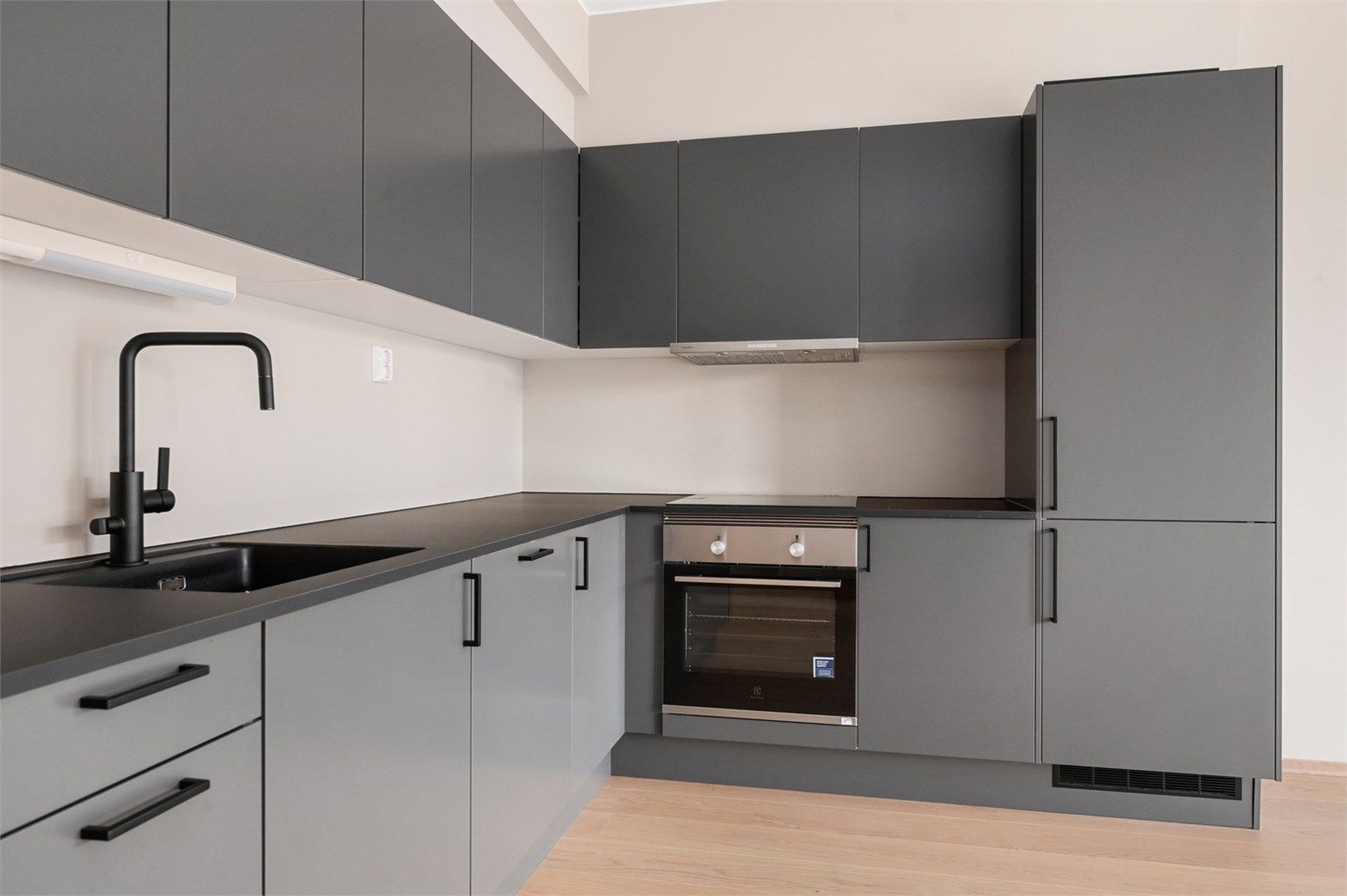 Kjøkkenet er utstyrt med innredning med mørke glatte fronter, benkeplate i laminat med nedfelt oppvaskkum med blandebatteri.