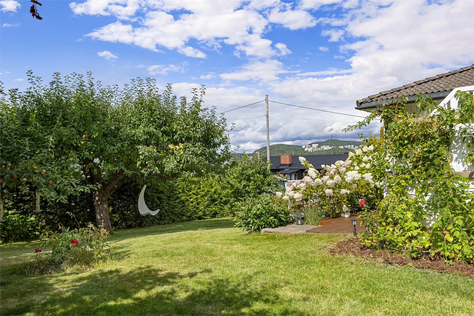 Den pent opparbeidede hagen byr på plen, frukttrær og variert beplantning og gir en grønn og trivelig ramme rundt boligen.