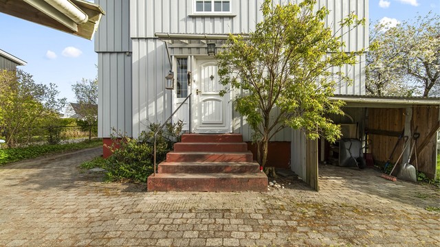 Praktisk adkomst på baksiden av huset med steinlagt uteplass.