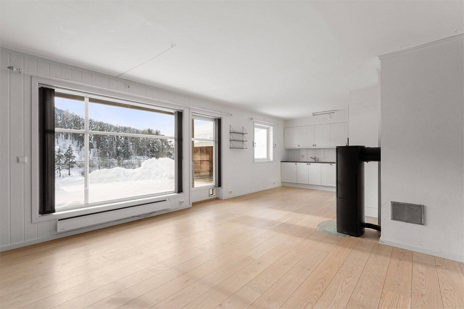 Store vindusflater gir rikelig med lys og en åpen atmosfære i stue- og kjøkkenområdet.