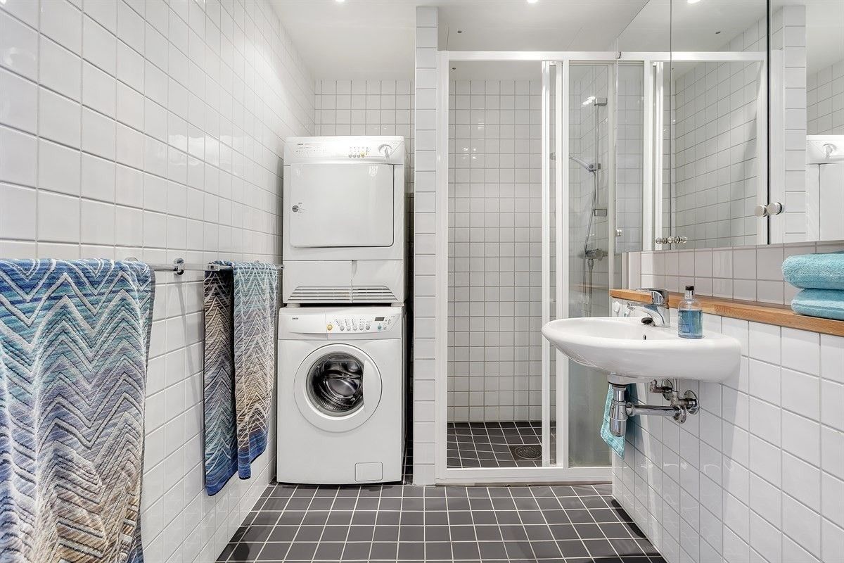 Pent flislagt bad med vaskemaskin og tørketrommel.