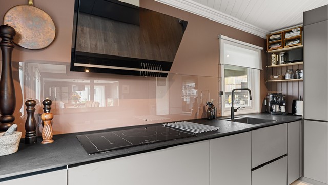 Kjøkkenventilator med utvendig avtrekk og benkeplate i kompaktlaminat med nedfelt induksjonstopp.