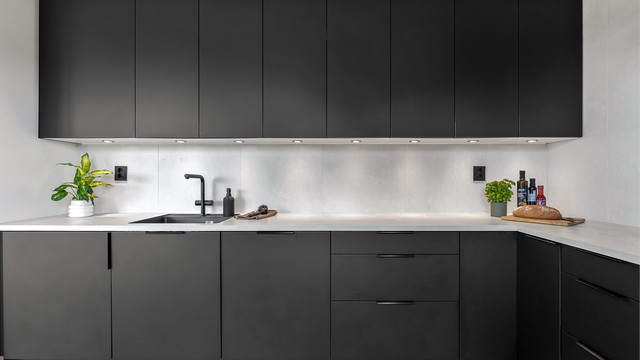 Designa kjøkken fra 2022 med glatte fronter, kjøkkenøy og benkeplate med laminert overflate. Nedfelt kjøkkenvask med armatur. Belysning under benkeskap og stikkontakter over kjøkkenbenk.