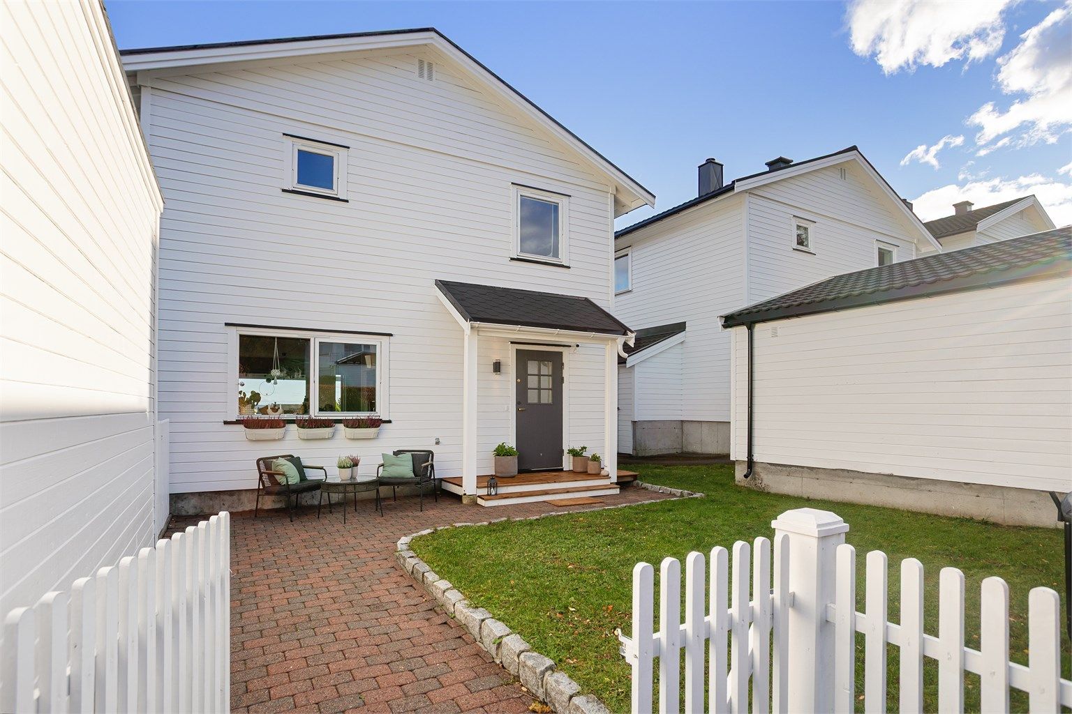 Pent opparbeidet uteområde med belegningsstein, gjerde og plen