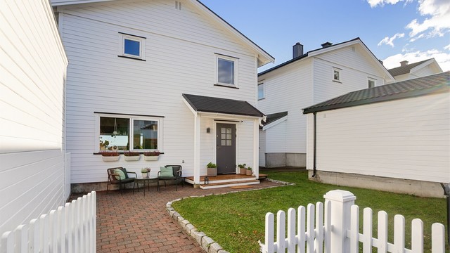 Pent opparbeidet uteområde med belegningsstein, gjerde og plen