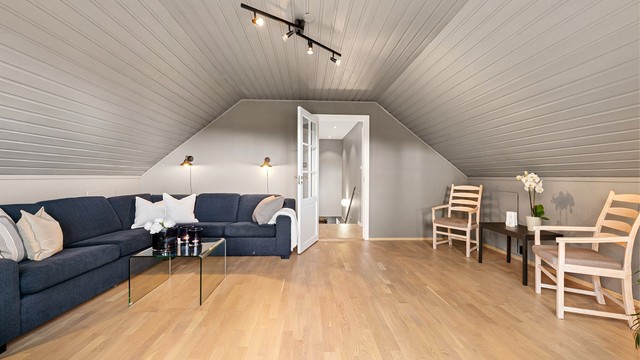 Romslig loftstue med god plass til en sofagruppe.