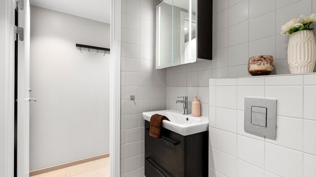 Badet har vegghengt toalett, servantinnredning og speilskap med belysning. Vannrør av typen rør-i-rør.