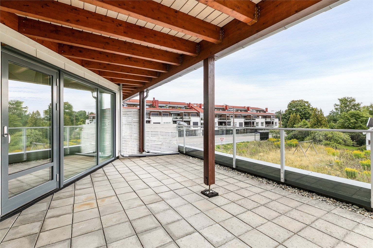 Mens terrassens ytre og åpne del er solfylt, er det svalende skygge å oppdrive under overbygget.