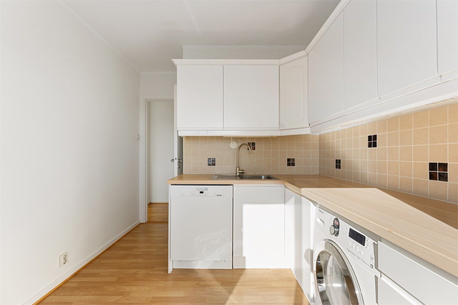 Kjøkkeninnredningen har glatte fronter og en benkeplate i laminat som gir gode arbeidsflater.