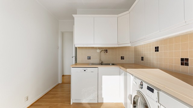 Kjøkkeninnredningen har glatte fronter og en benkeplate i laminat som gir gode arbeidsflater.