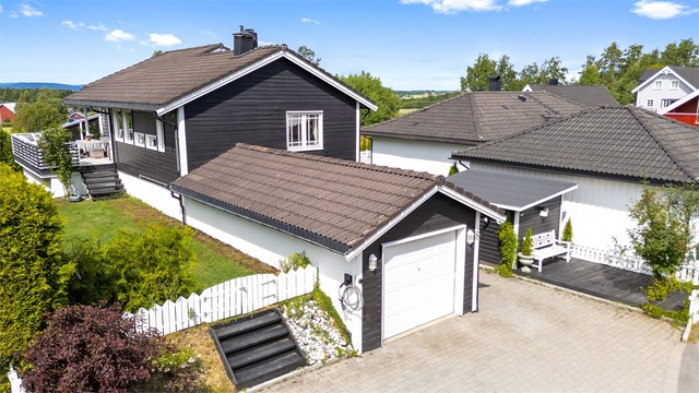 Enebolig med garasje og steinbelagt gårdsplass.