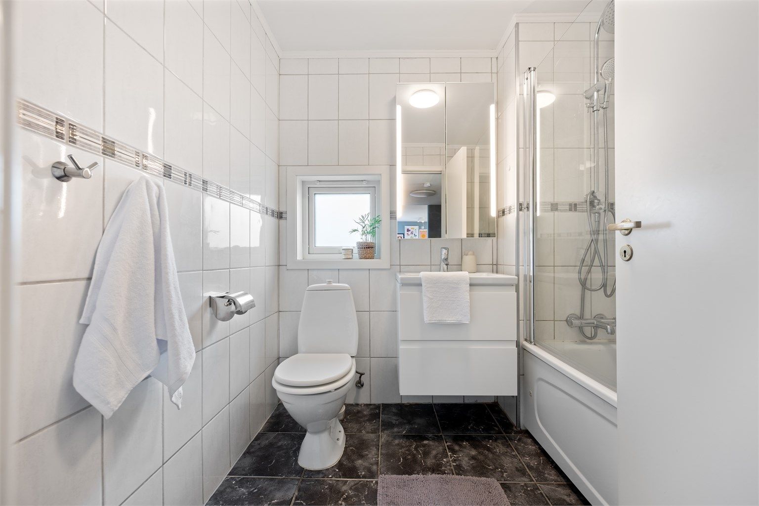 Bad fra byggeår er helfliset med varme i gulv. Det er mørke fliset på gulv og lyse på vegg. Det er lagt nyere flis oppå belegg fra byggeår.  Innredningen med vask og speil var oppgradert i 2020. 