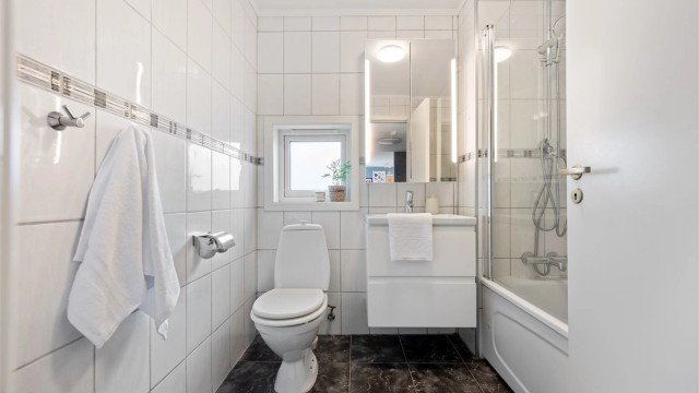 Bad fra byggeår er helfliset med varme i gulv. Det er mørke fliset på gulv og lyse på vegg. Det er lagt nyere flis oppå belegg fra byggeår. Innredningen med vask og speil var oppgradert i 2020.