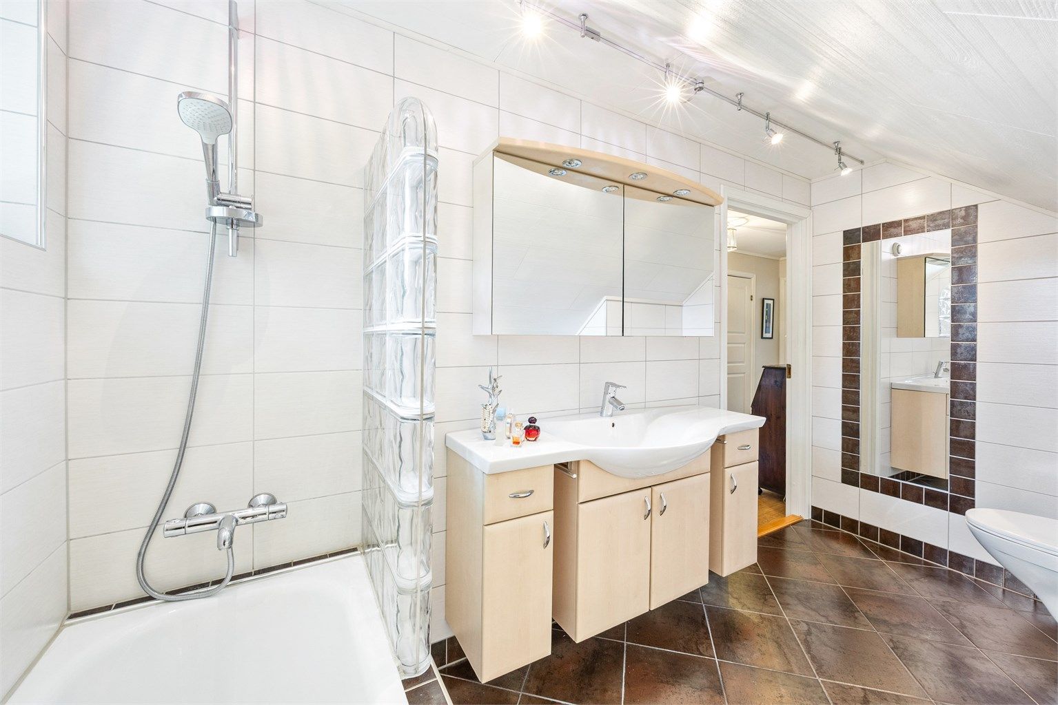 Flislagte vegger og vegghengt toalett på badet i loftsetasjen.