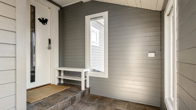 Overbygd inngangsparti med flislagt gulv og elektronisk kodelås på døren.