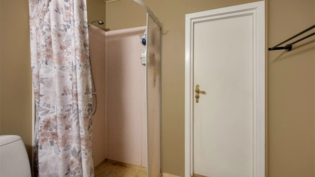Badet er innredet med dusjnisje med forheng, servant med underskap og toalett.