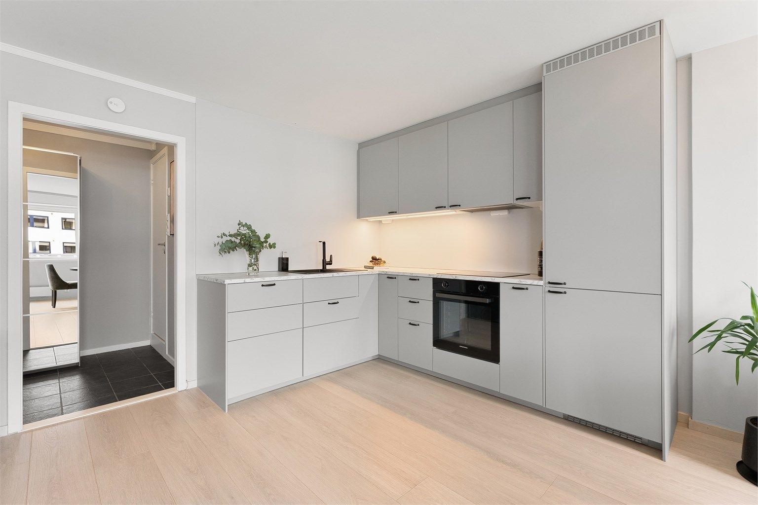 Den åpne løsningen binder kjøkken og stue sammen, med gjennomgående laminatgulv som skaper en helhetlig følelse.