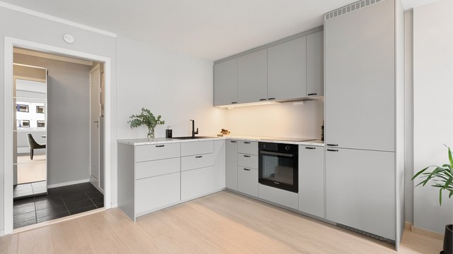 Den åpne løsningen binder kjøkken og stue sammen, med gjennomgående laminatgulv som skaper en helhetlig følelse.