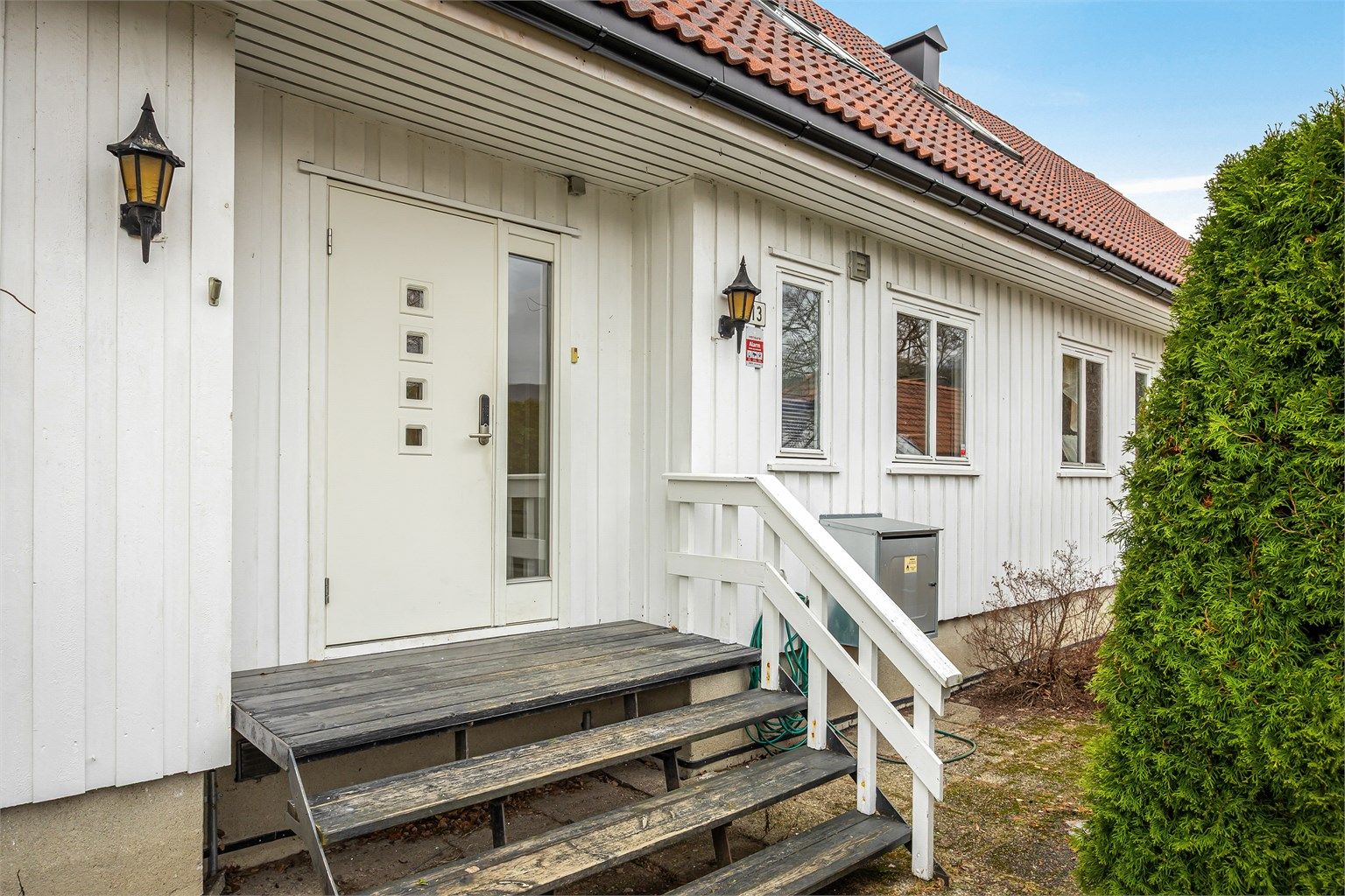 Gruset gårdsplass med trapp opp til inngangspartiet 