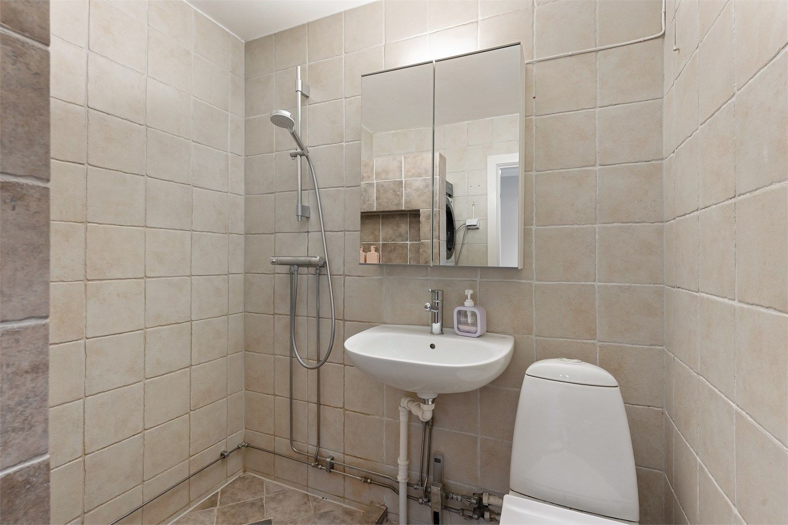 Badet er utstyrt med servant, speilskap med belysning og toalett.