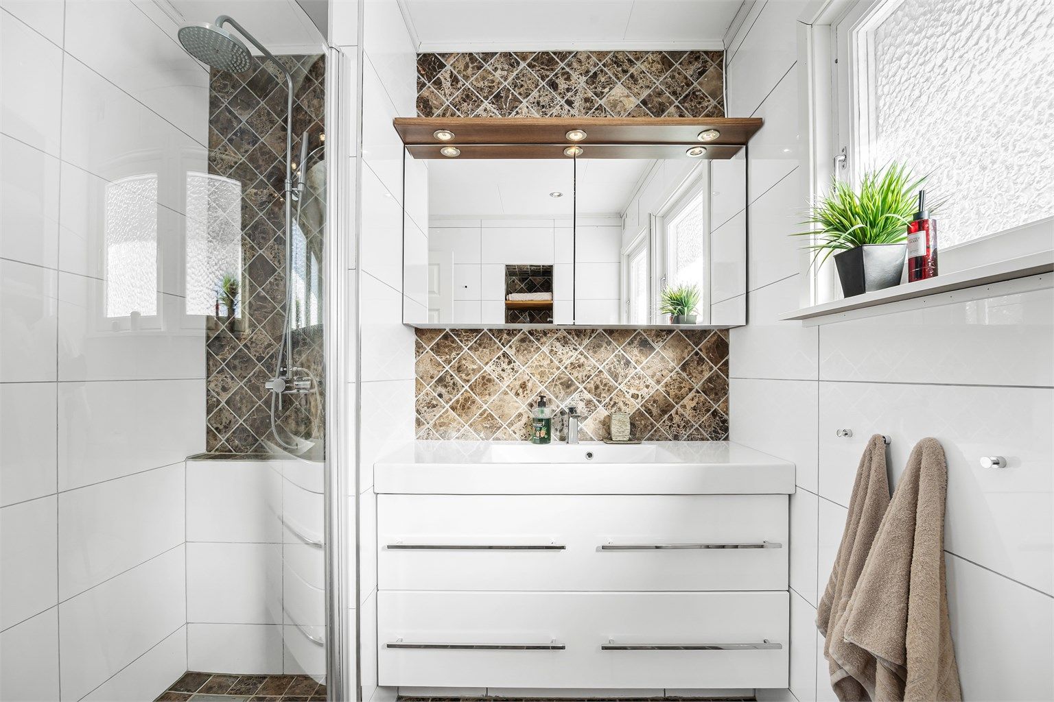 Badet har dusjnisje med dusjvegg-/dør av glass og regnfallsdusj.