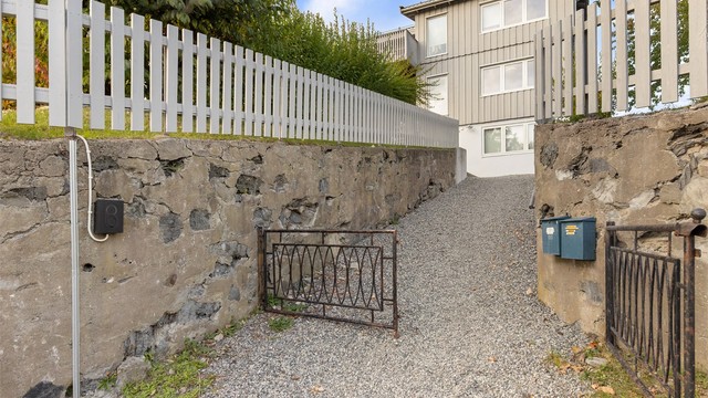 Gruslagt innkjøring med forstøtningsmur i naturstein og montert lader for elbil.