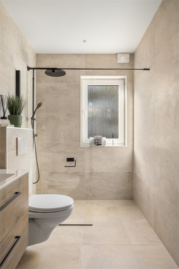 Dusjnisje med glassvegg, regnfallsdusj og en dekorativ mosaikkvegg.